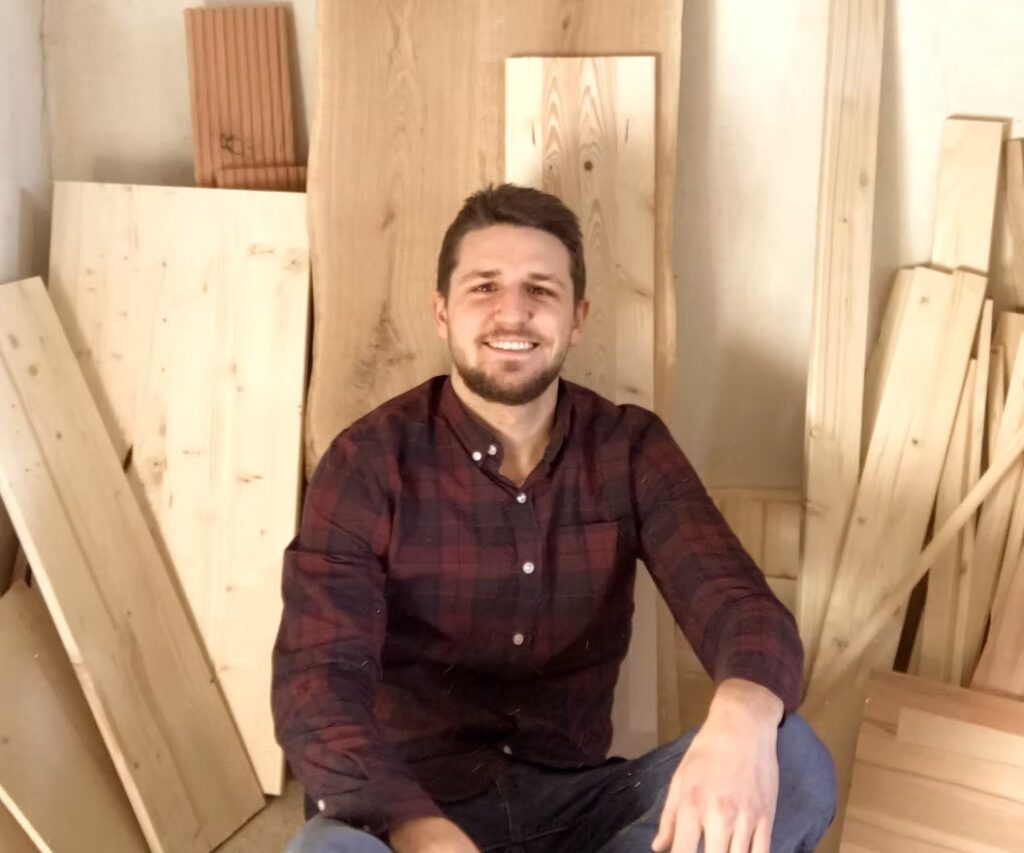 Photo de l'artisan créateur devant des planches de bois